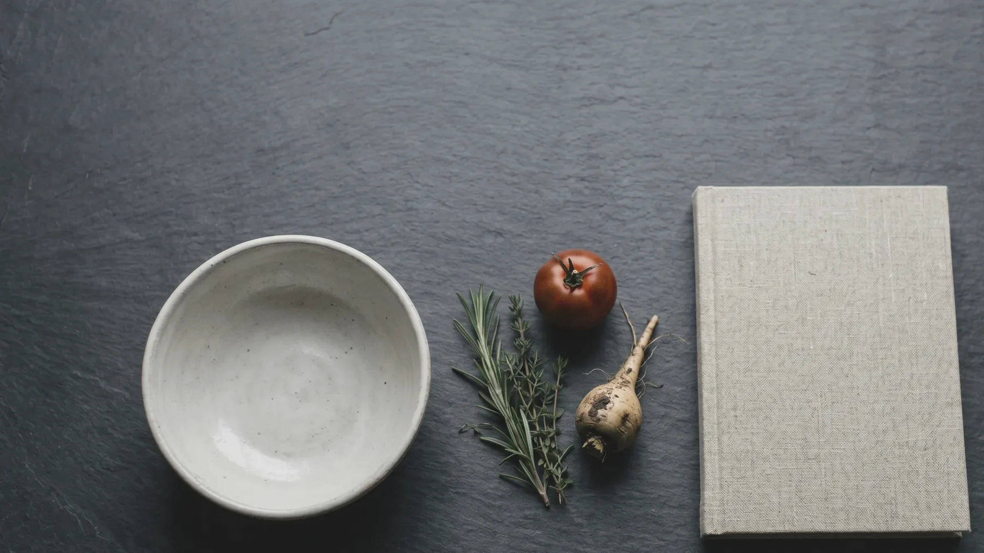Detalle frío de una mesa de pizarra con producto de temporada y una libreta